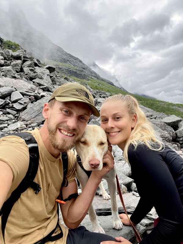 couple with their dog on the side of a mountain