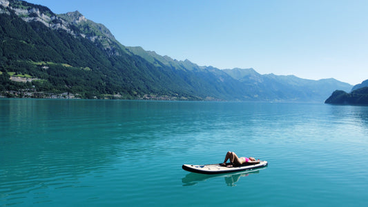 Women floating on a paddleboard in the turquoise Lake Brienz
